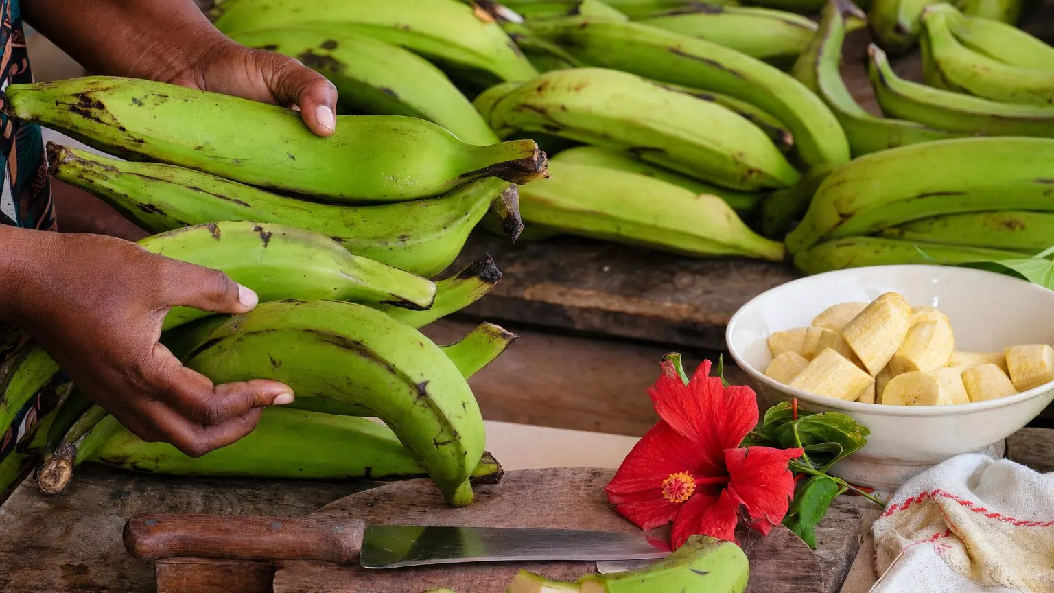 Bananes plantain vertes sur un étal de marché, prêtes à éplucher pour une banane plantain verte bouillie ou frite